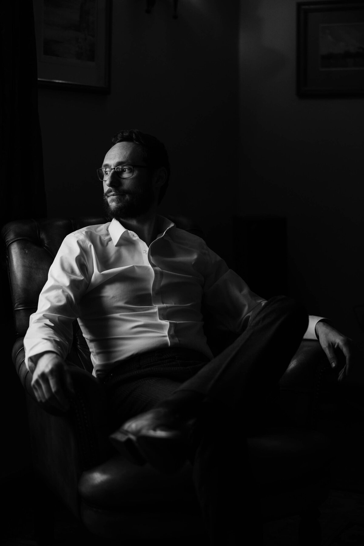 Black and white portrait of a groom looking out of the window