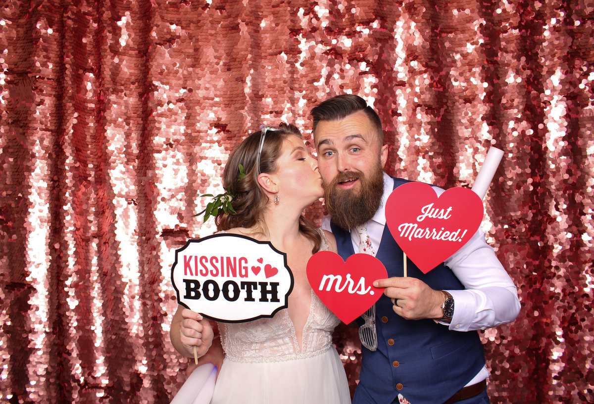 Bride kisses her Groom's cheek in a photo booth
