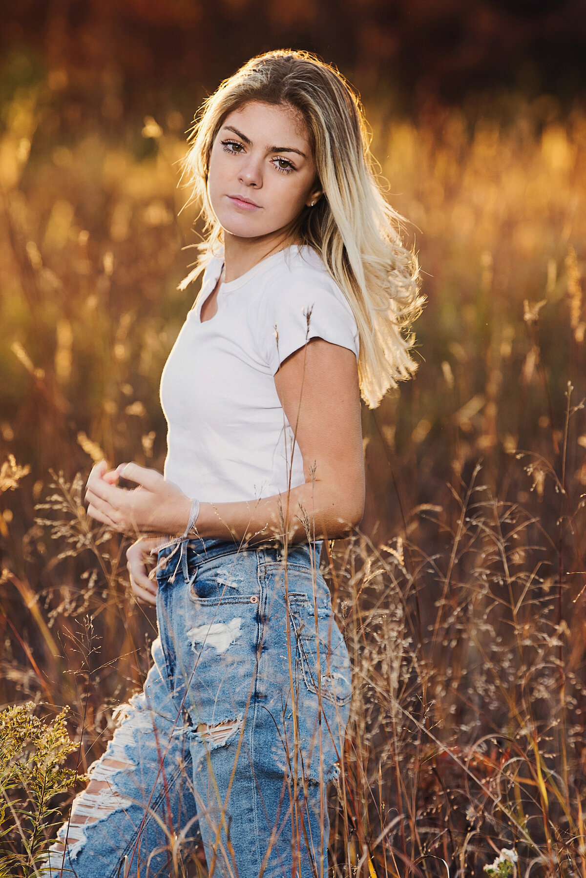 girl holding grass in nature with jeans and white tshirt