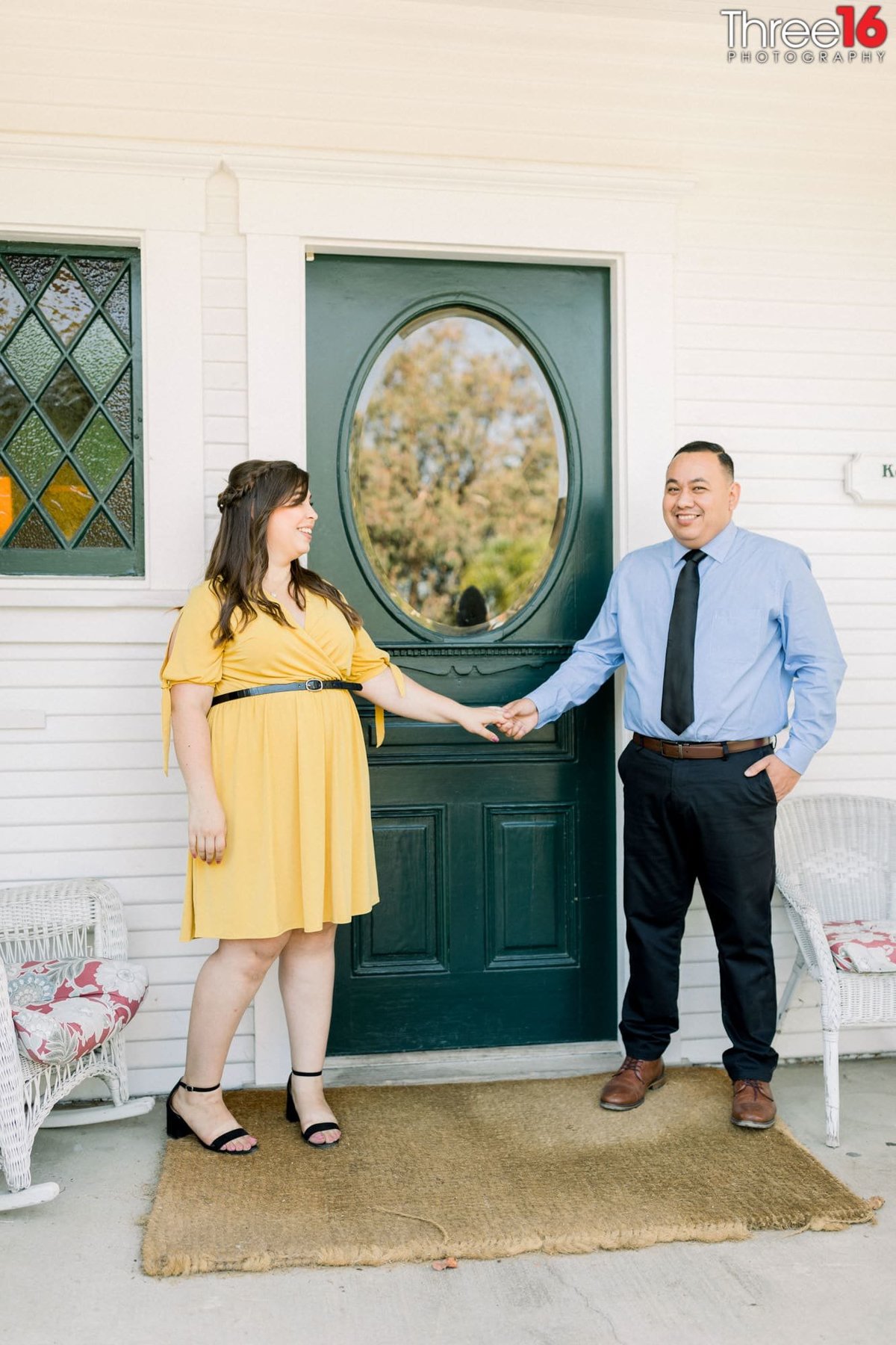 Engaged couple hold hands in front of the Heritage Museum OC's front door