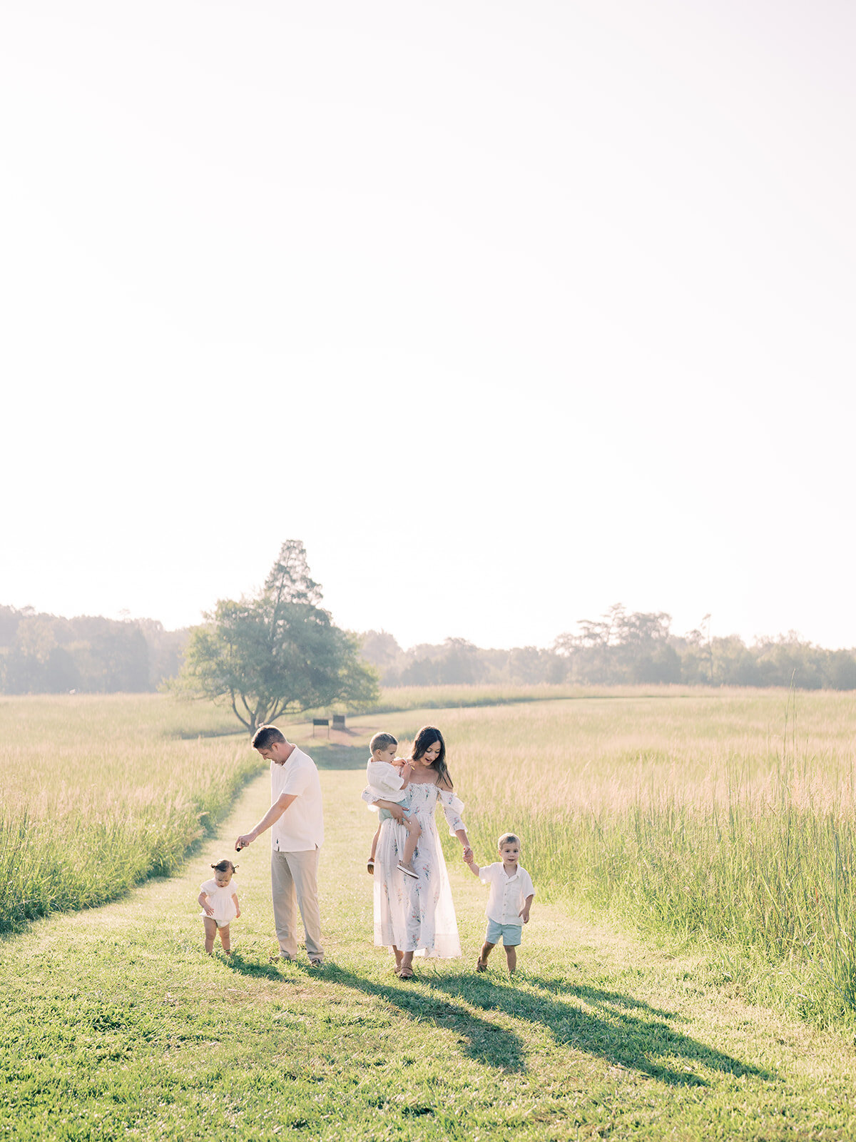 A family of five walks in a grassy field in Manassas, VA.
