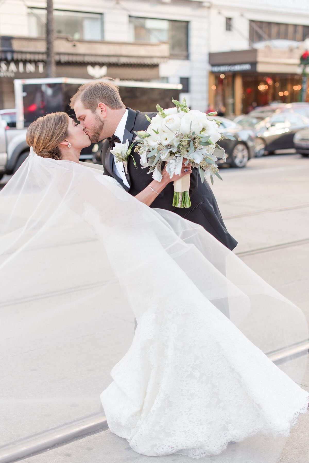 couple kissing in busy city street on wedding day