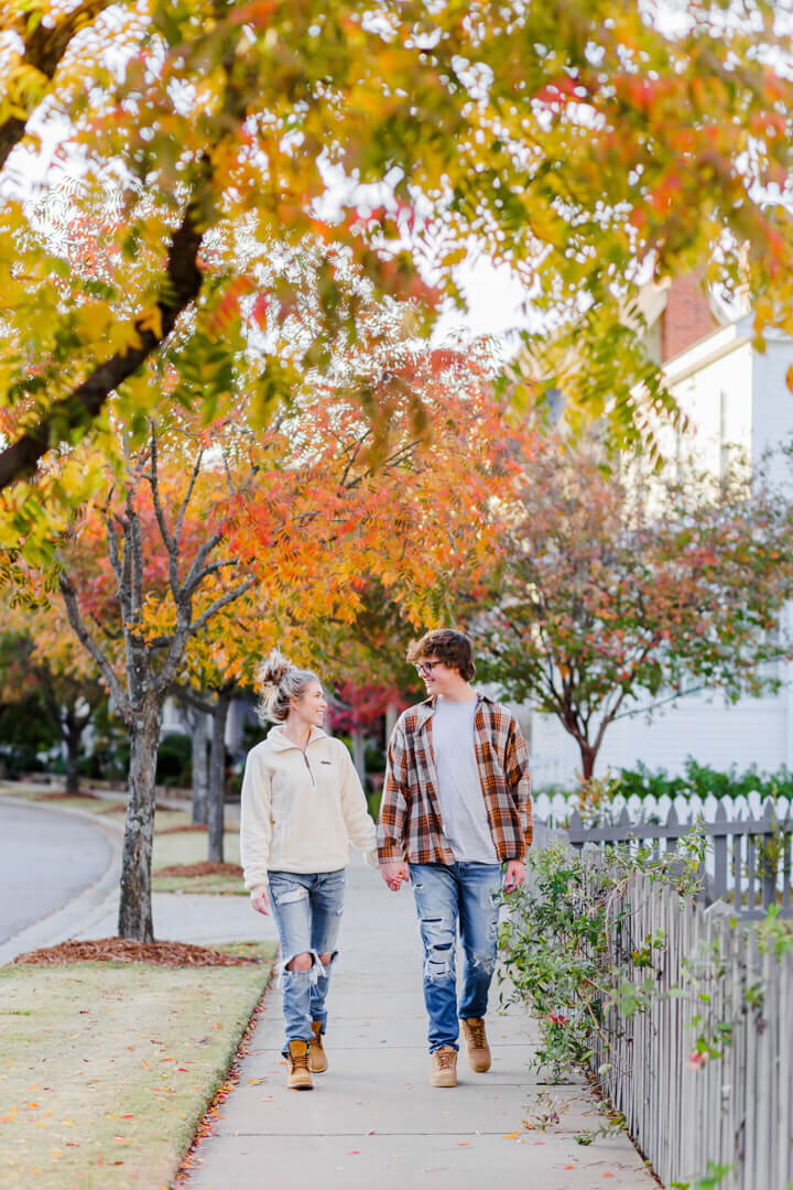 A guy and girl walk towards the camera holding hands in Conway, AR. Captured by Wedding Photographer, Photography by Karla