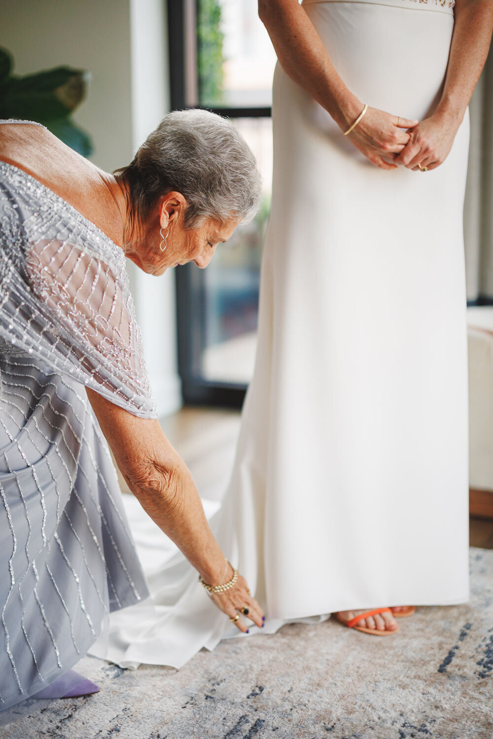 Mother of the bride helping bride fix her dress