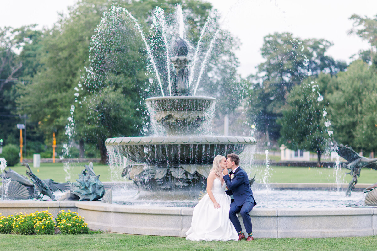 Bride and groom kissing and sitting by fountain representing colorful Boston wedding photography