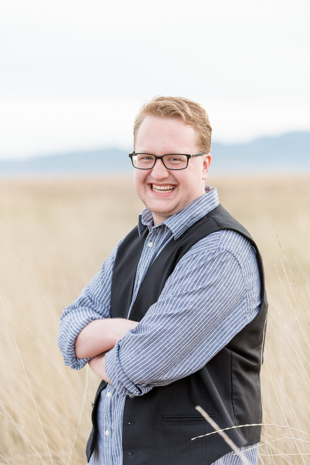 senior boy laughs at the camera while folding his arms in layton utah