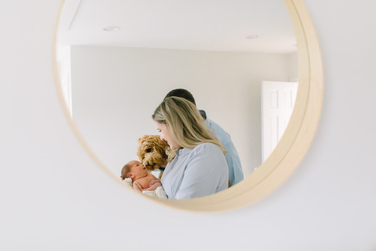 young family in baby nursery photographed through mirror
