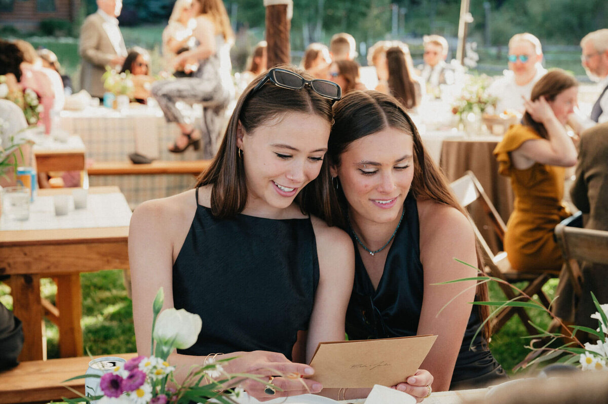 Wedding guests reading handwritten notes at the reception table. 