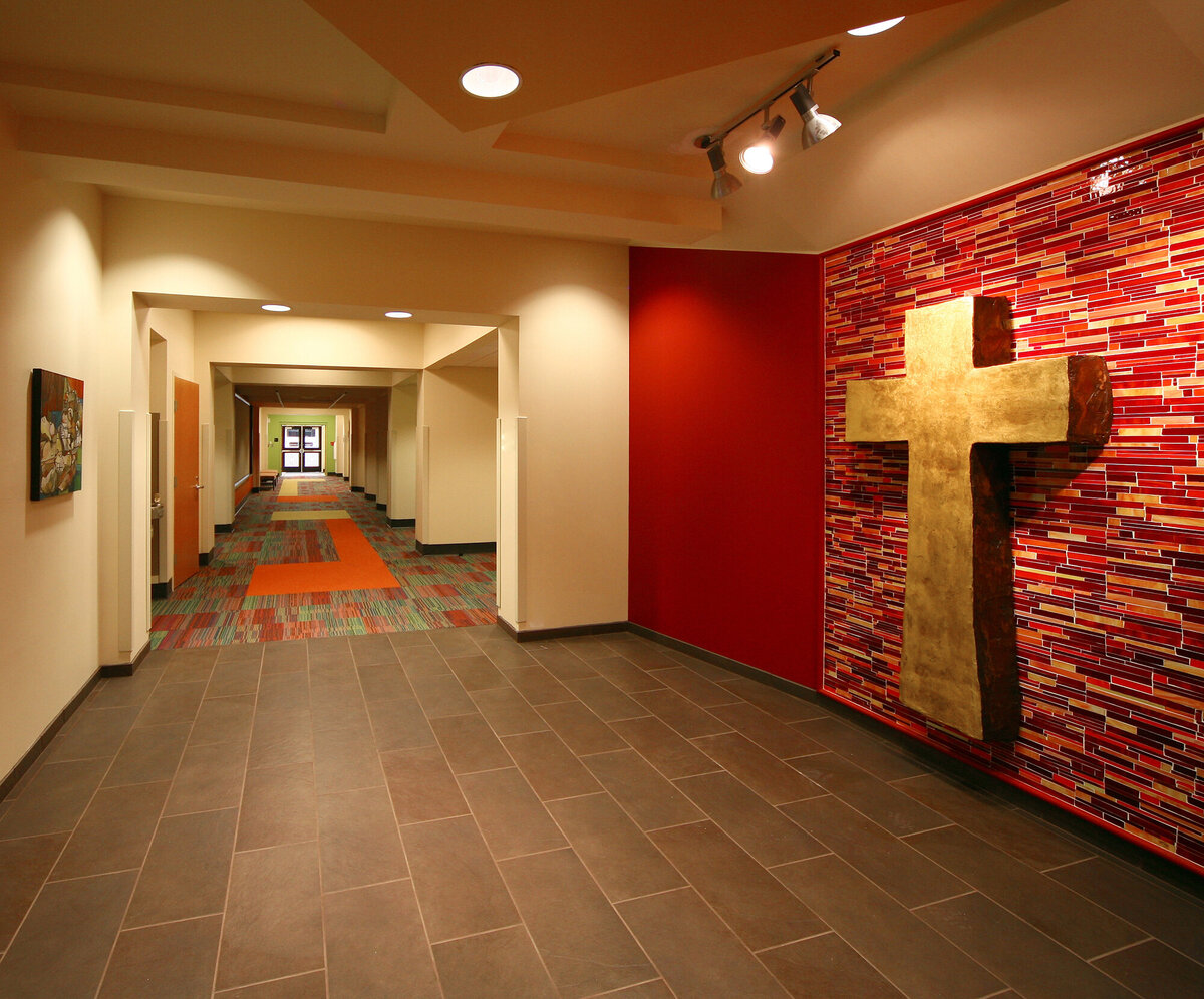 interior corridor with red wall and cross at Wesleyan School Fine Arts