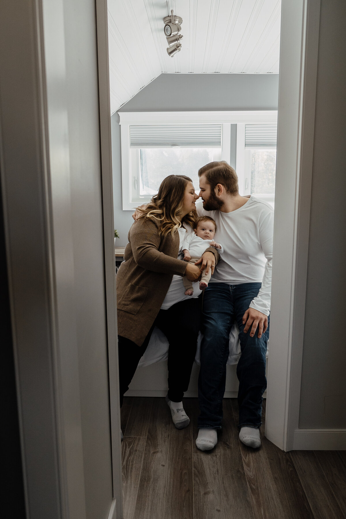 couple kissing holding baby