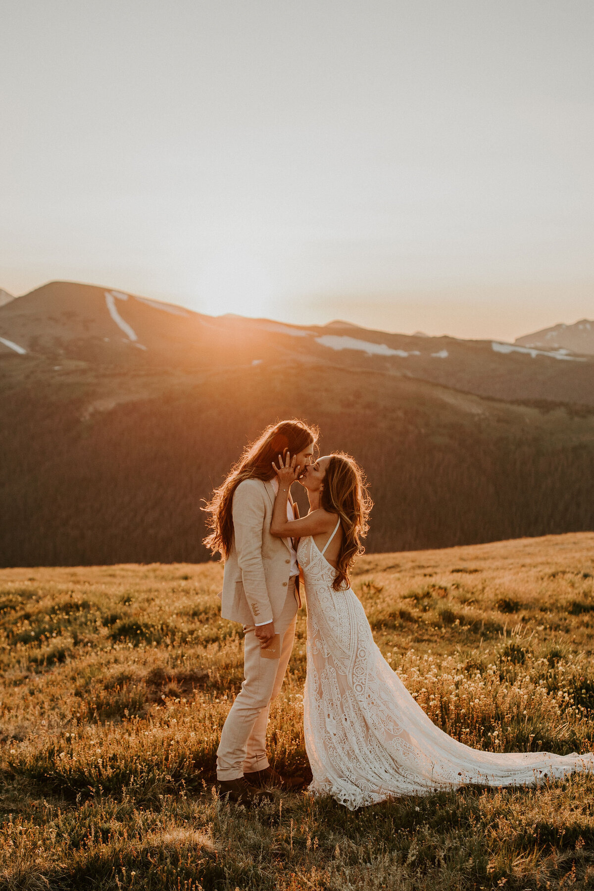 bride and groom kissing wearing a white wedding gown and ivory tuxedo at golden hour in the mountains