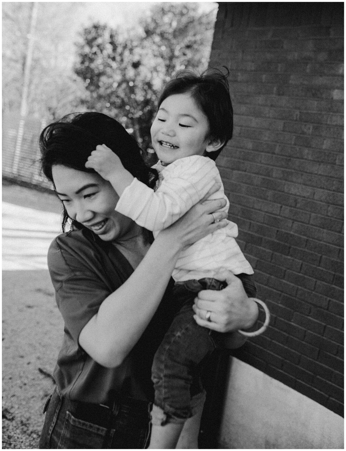 Child playing with mothers hair as she carries him at  garden family session in Austin by Amber Vickery Photography