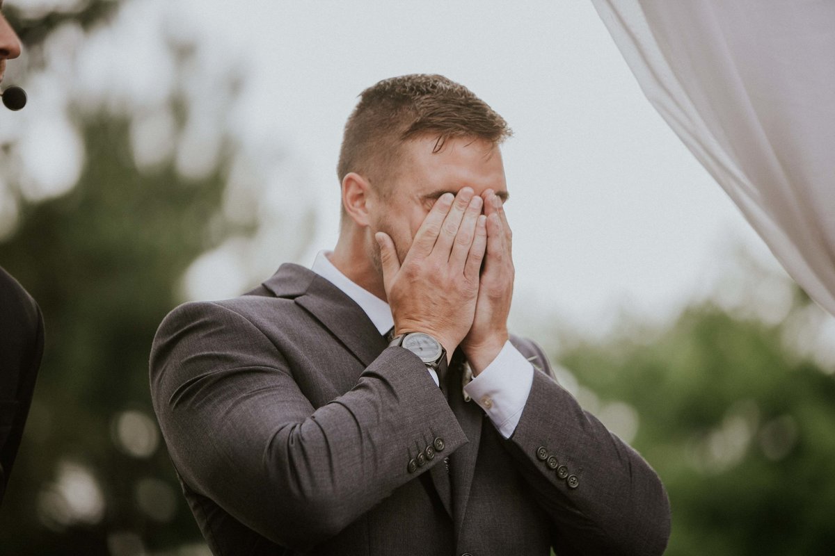 Groom covers his eyes after seeing his bride at their mustard seed gardens wedding ceremony