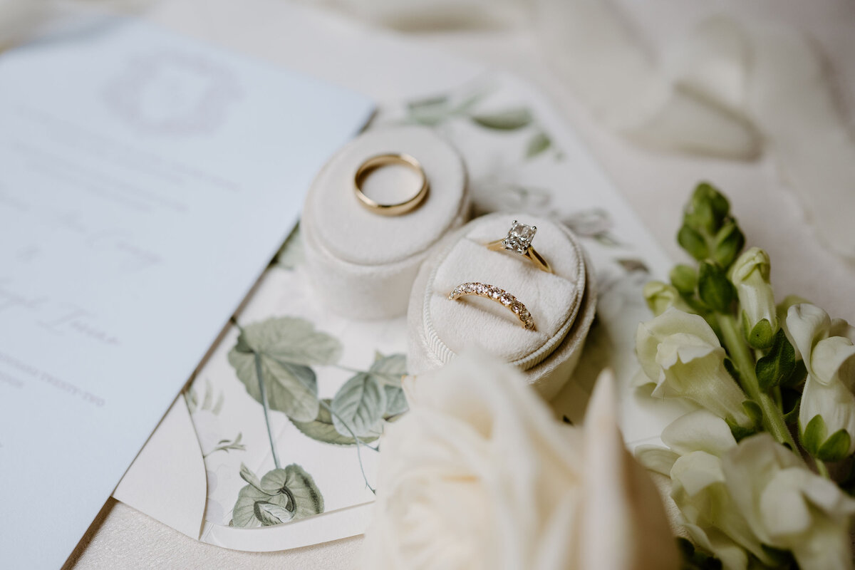Luxury wedding invitation with floral liner, gold wedding rings in velvet box, and wedding day stationery.