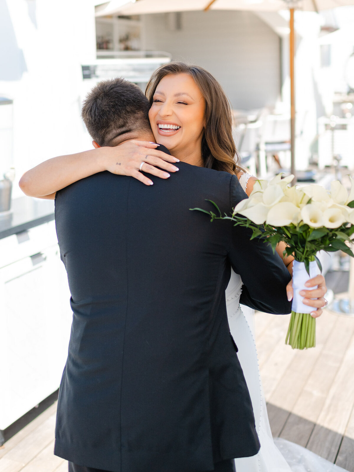 Bride embraces groom with a joyful smile during their first look at Lido House, Newport Beach.