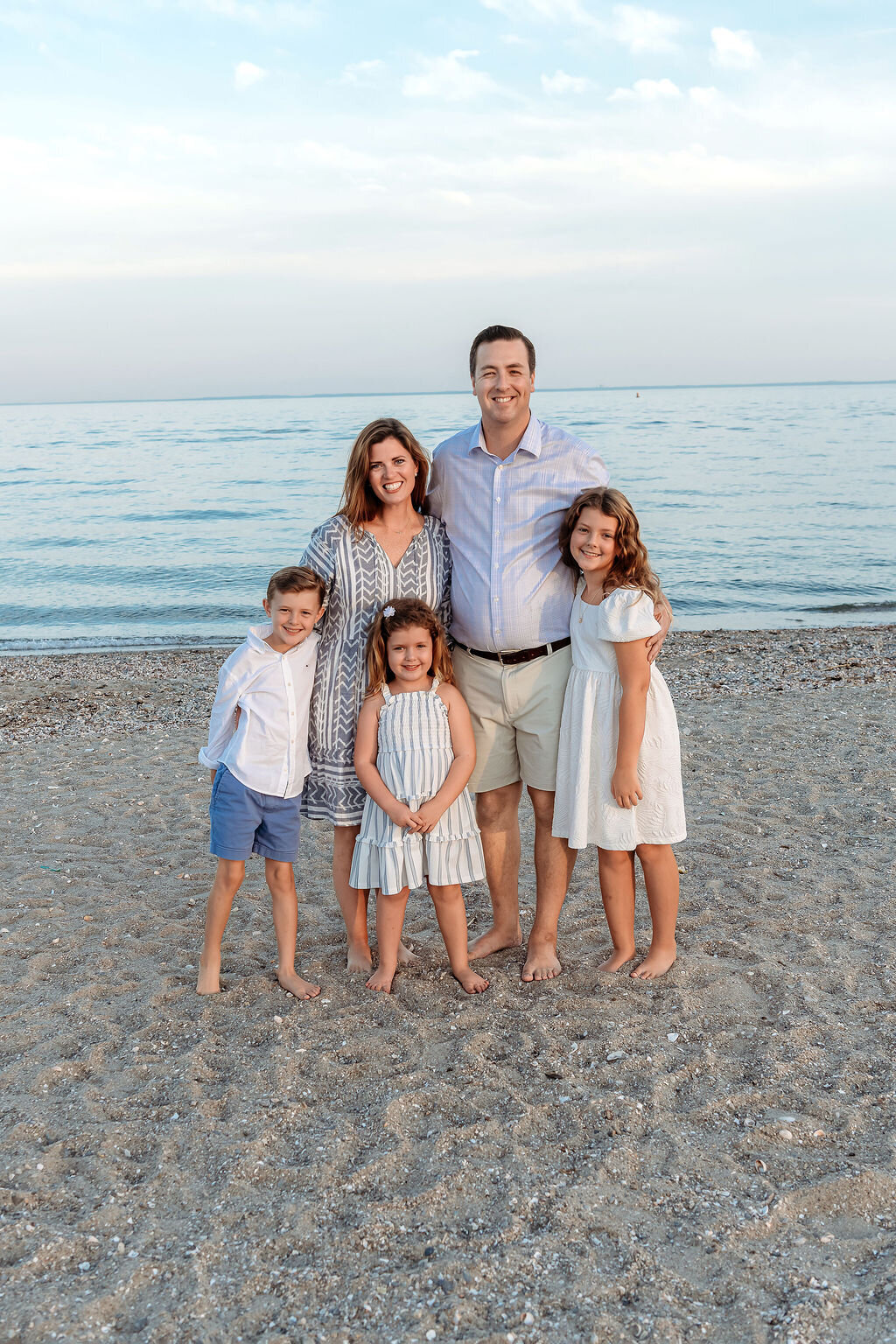 Connecticut family photographer documents family of five in coastal setting wearing coordinated blue and white beach outfits
