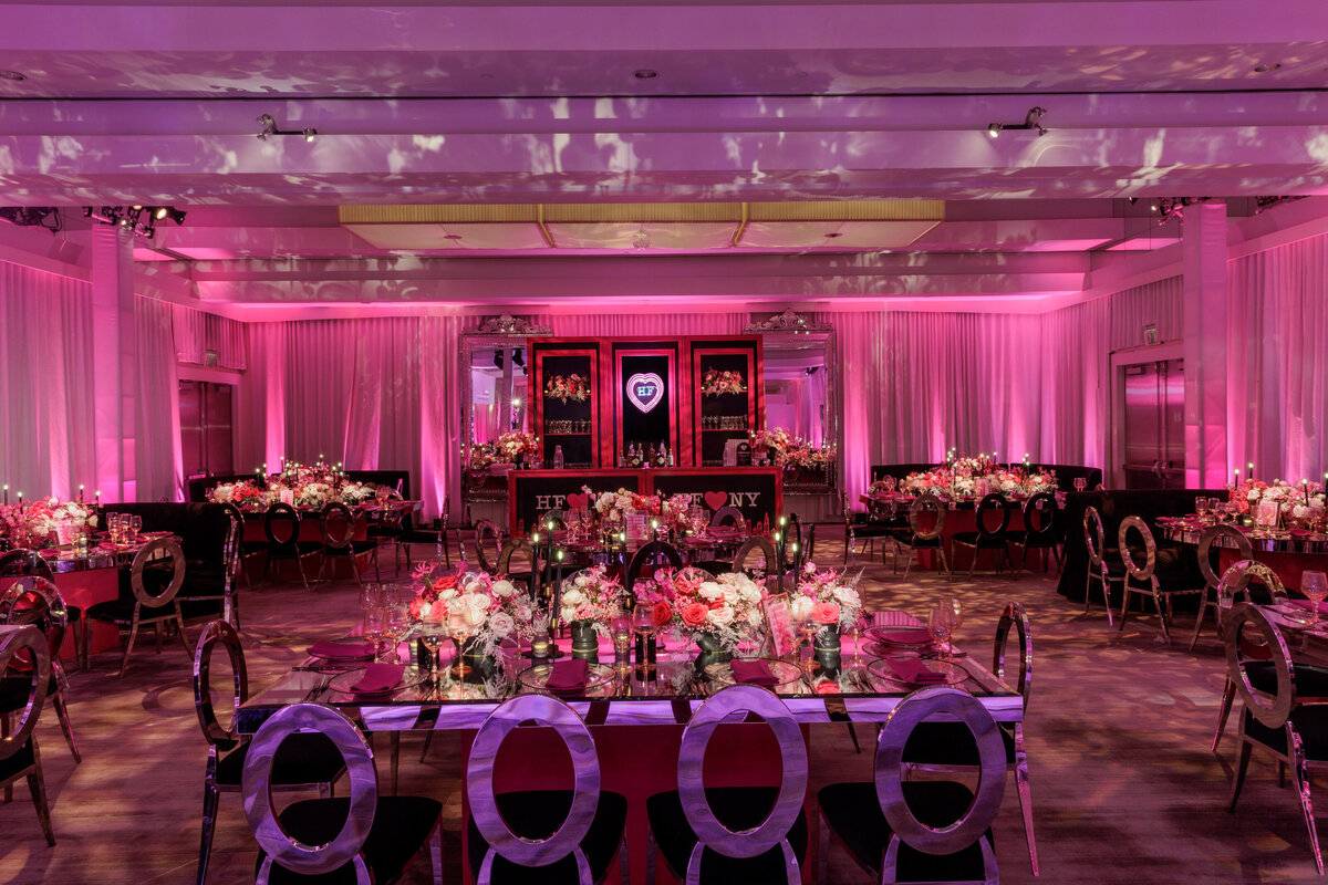 A ballroom decorated in pink lights and tables