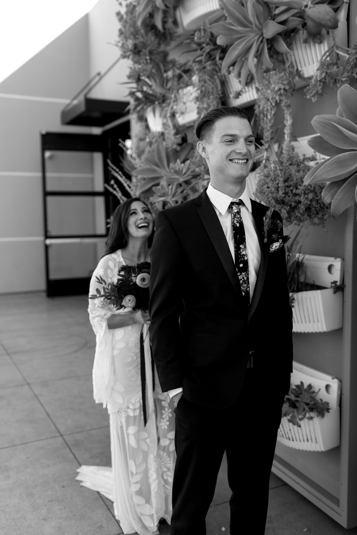 Bride walking up behind groom for their first look. Both excited smiles and waiting with anticipation.