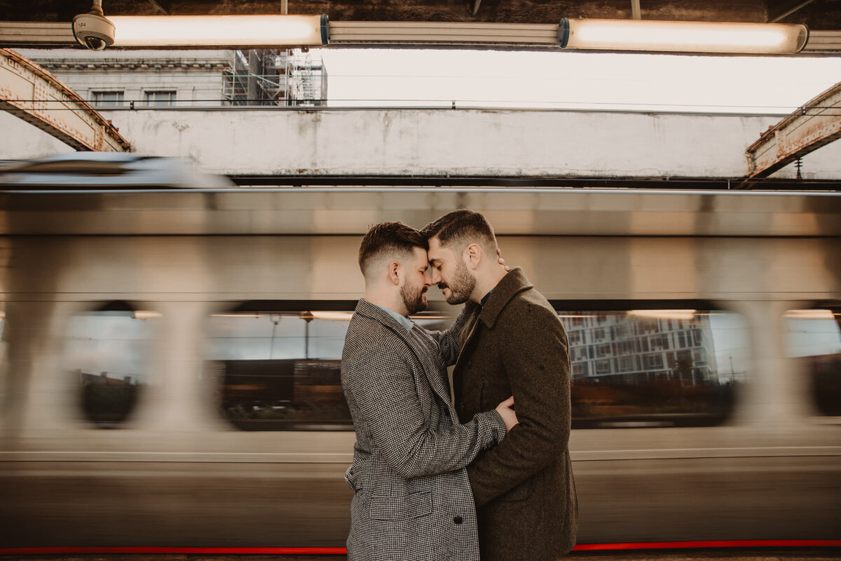 A couple standing forehead to forehead in front of a train 