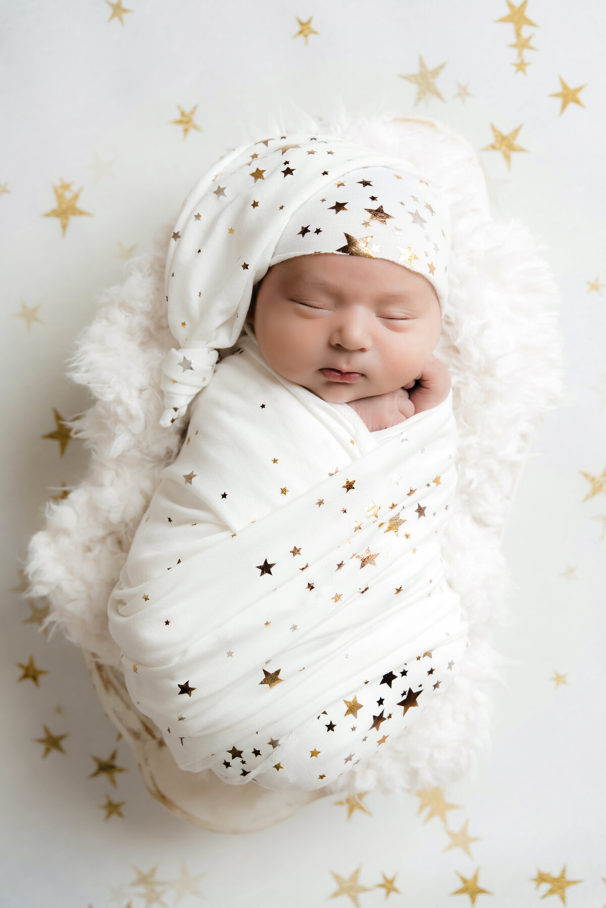 Newborn baby wrapped in star wrap sleeping in wooden bowl on star backdrop