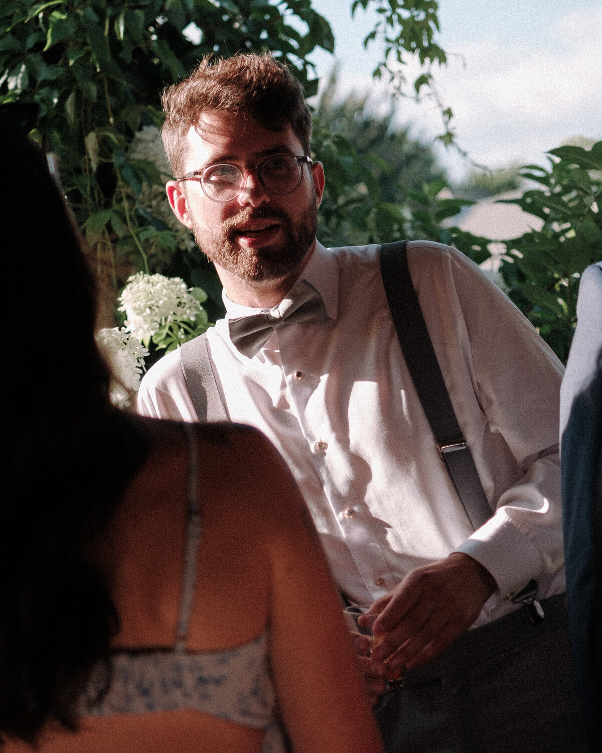 best man with glasses enjoys a drink during cocktail hour