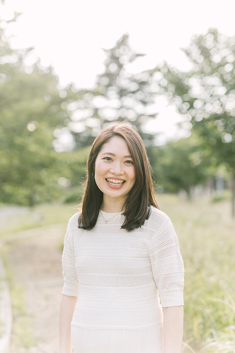 夕日の緑の中で笑顔で笑っている妊婦さんのマタニティフォト