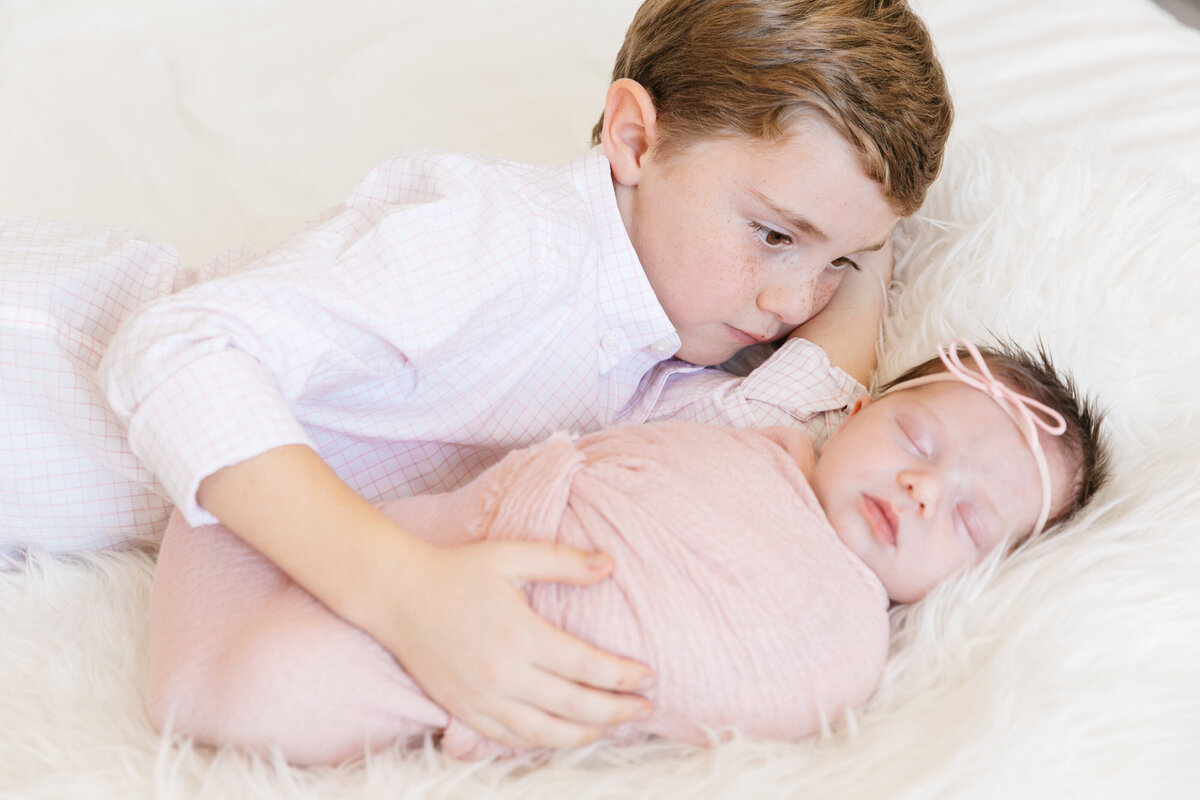 A young boy with his arm around his newborn sibling