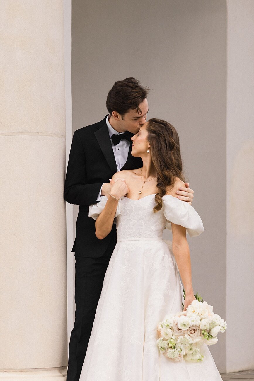 groom kisses bride on forehead with her back facing him