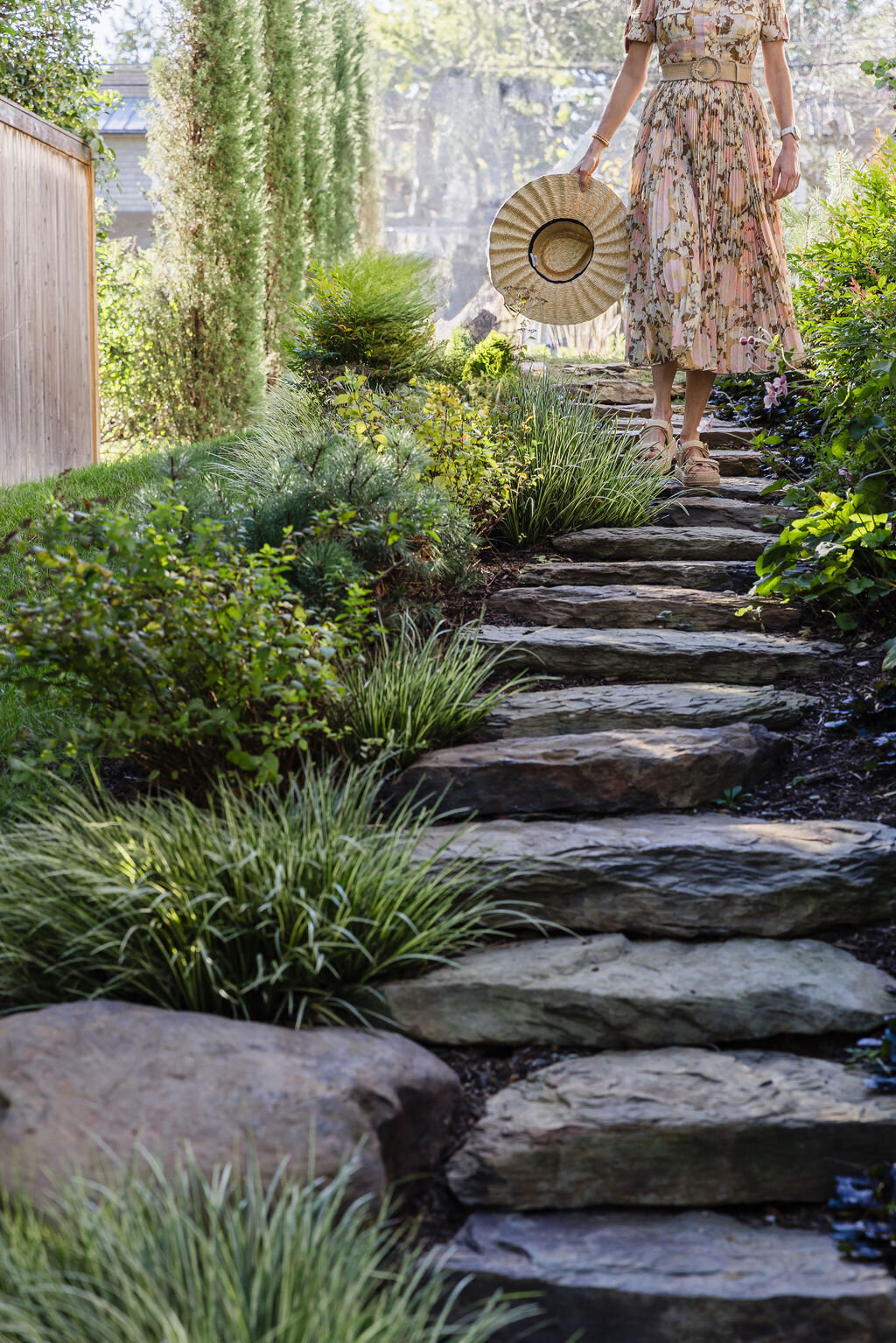 A rustic stone pathway lined with lush plants and colorful flowers.