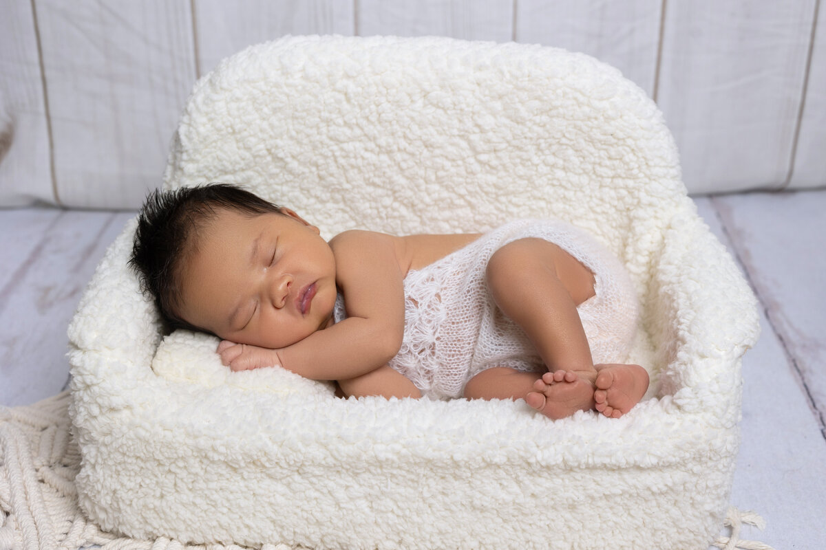 DMV - Photobyshai -Newborn laying with her hand on face on a cream couch