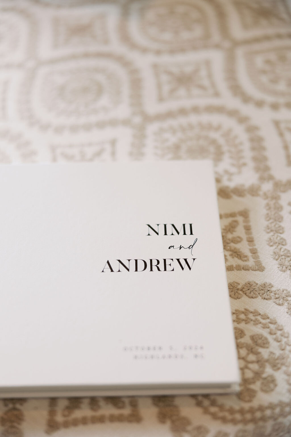 Minimalist white wedding album with black typography placed on textured linen during wedding day at Old Edwards Inn.
