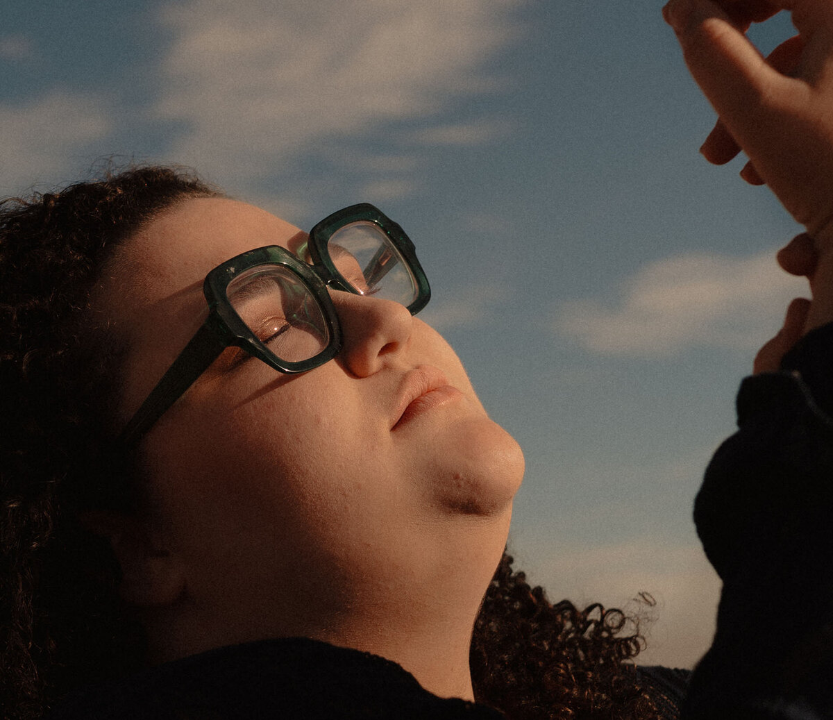 woman with glasses embraces the sun on her face as she poses in the outdoors in Bend, Oregon