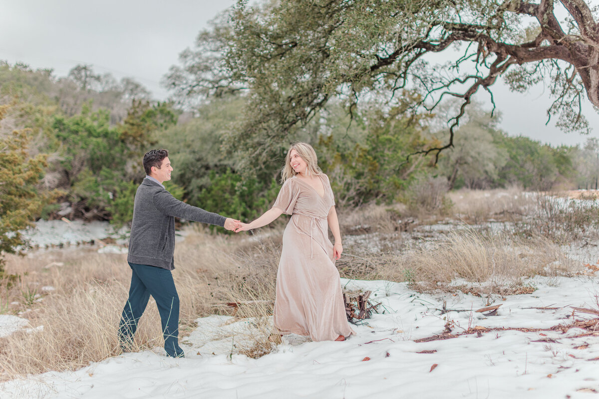 woman walks ahead of man with walking uphill in the snow  by New Braunfels wedding photographer Firefly Photography