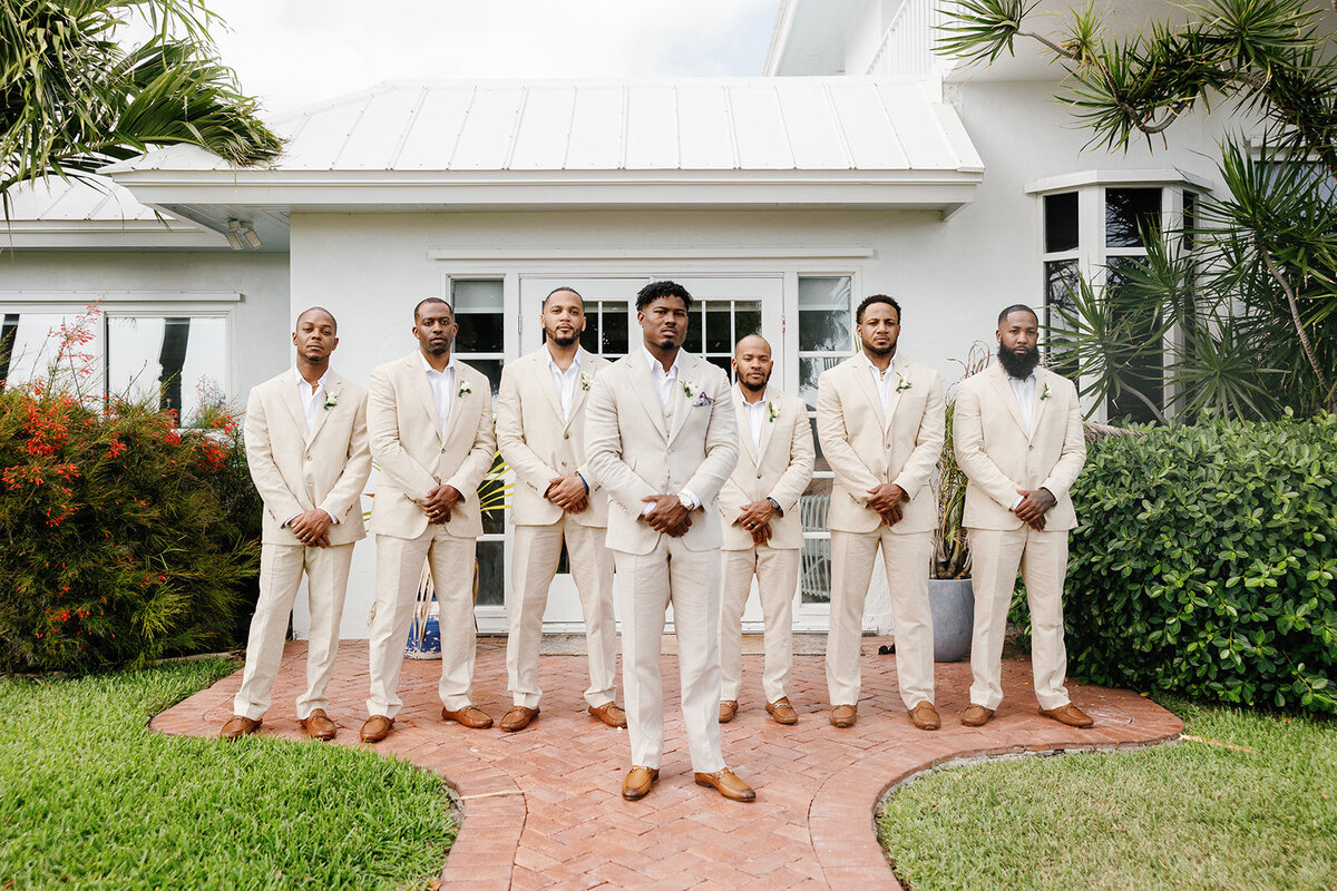 onathan and his groomsmen pose in beige suits in front of a tropical villa at Table Key, Islamorada. Photography by Claudia Amalia Wedding Photography.