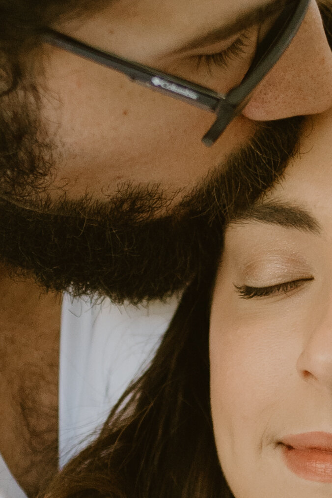 closeup of a man kissing his wife on the forehead.
