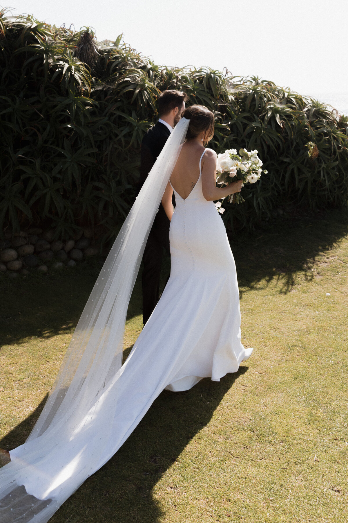 Bride and groom walking along the La Jolla cliffs in San Diego, captured in a refined documentary wedding photography style.