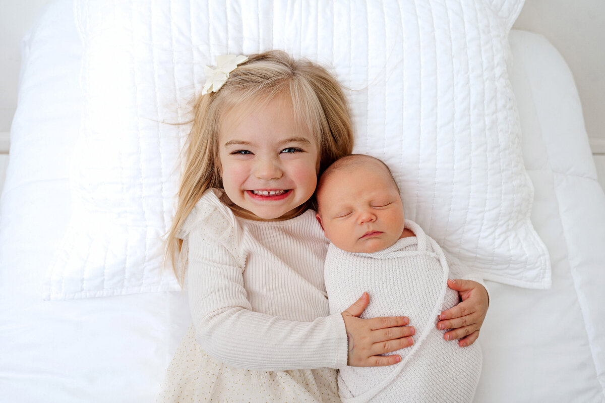 sibling smiling big during newborn photo session in pittsburgh studio