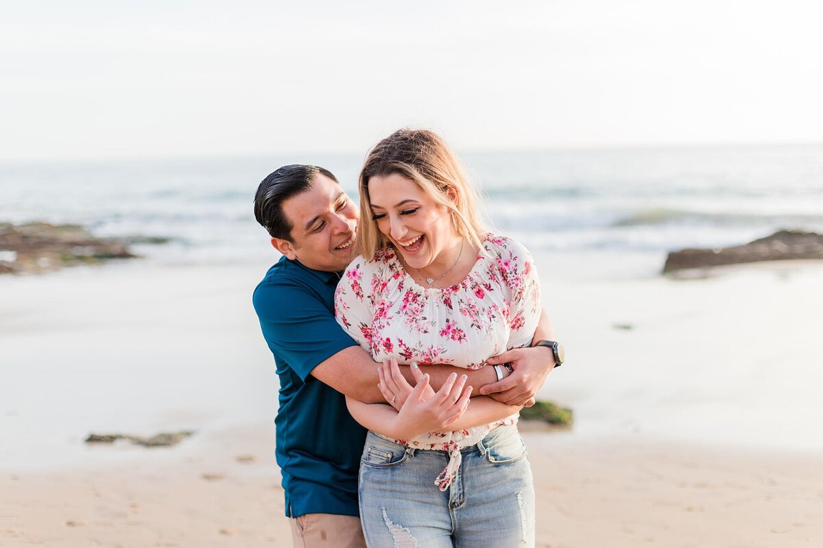 engaged couple laugh on the beach