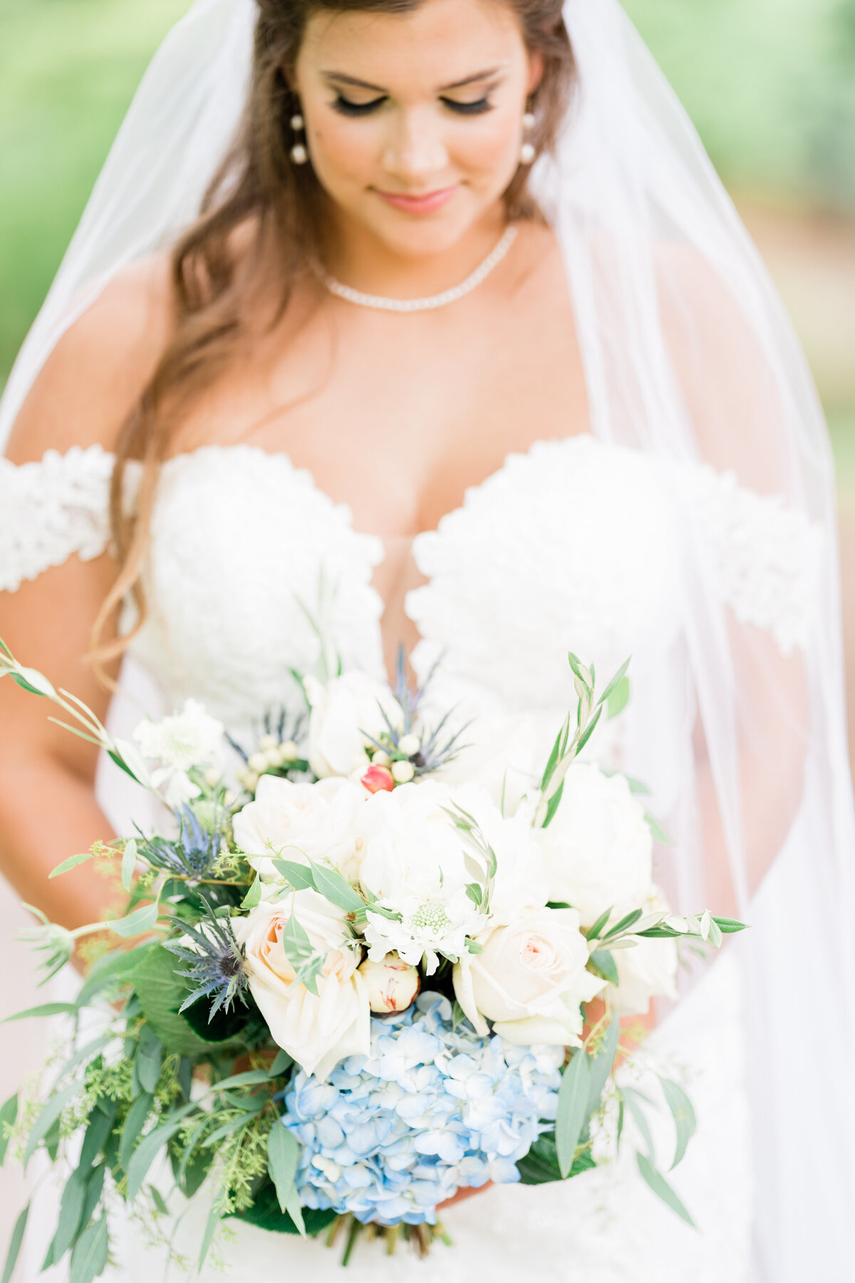 Bride looking down at white and blue bouquet