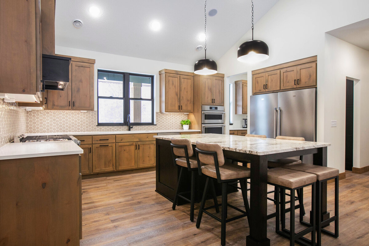 Open kitchen with dark cabinets, large island, and quartz countertops in an Elk River custom home
