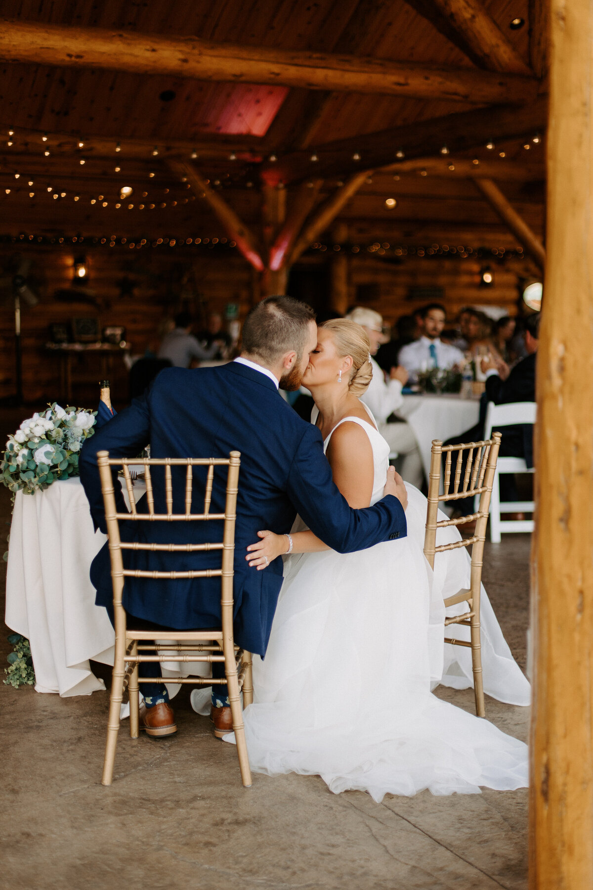 bride and groom sitting in chairs kissing each other