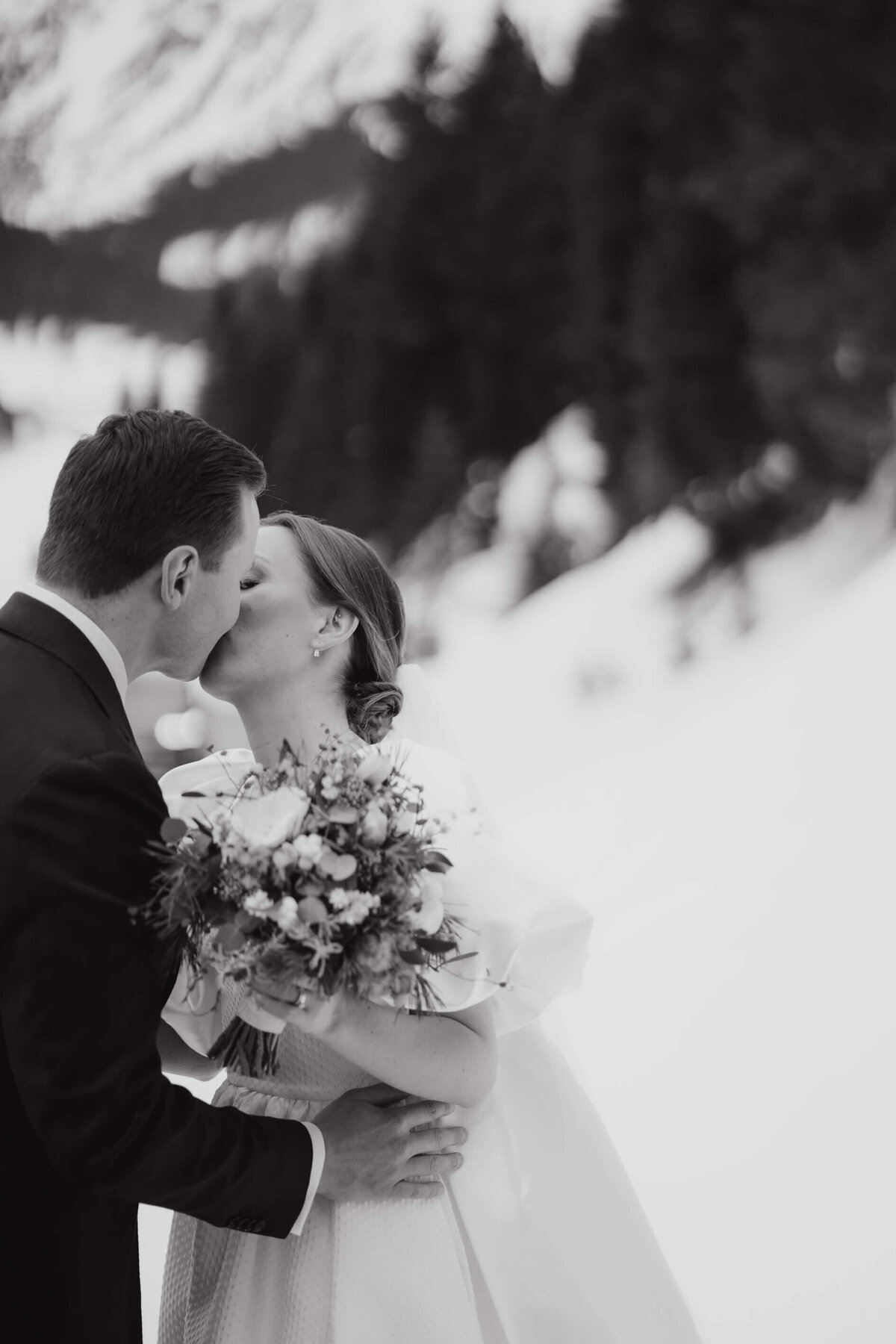 Winter wedding in the Alps captured by Vienna Photographer with bride and groom kissing