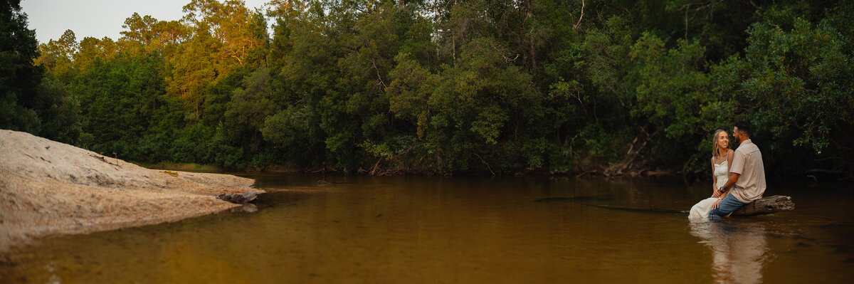 Couple seated along a creek in Florida for their engagement photos