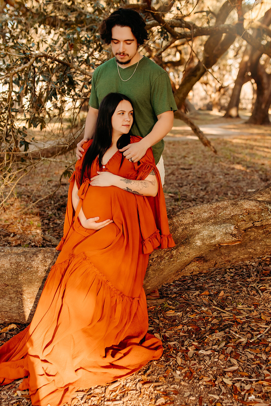 Hardin TX maternity portraits—couple seated outdoors with focus on baby bump