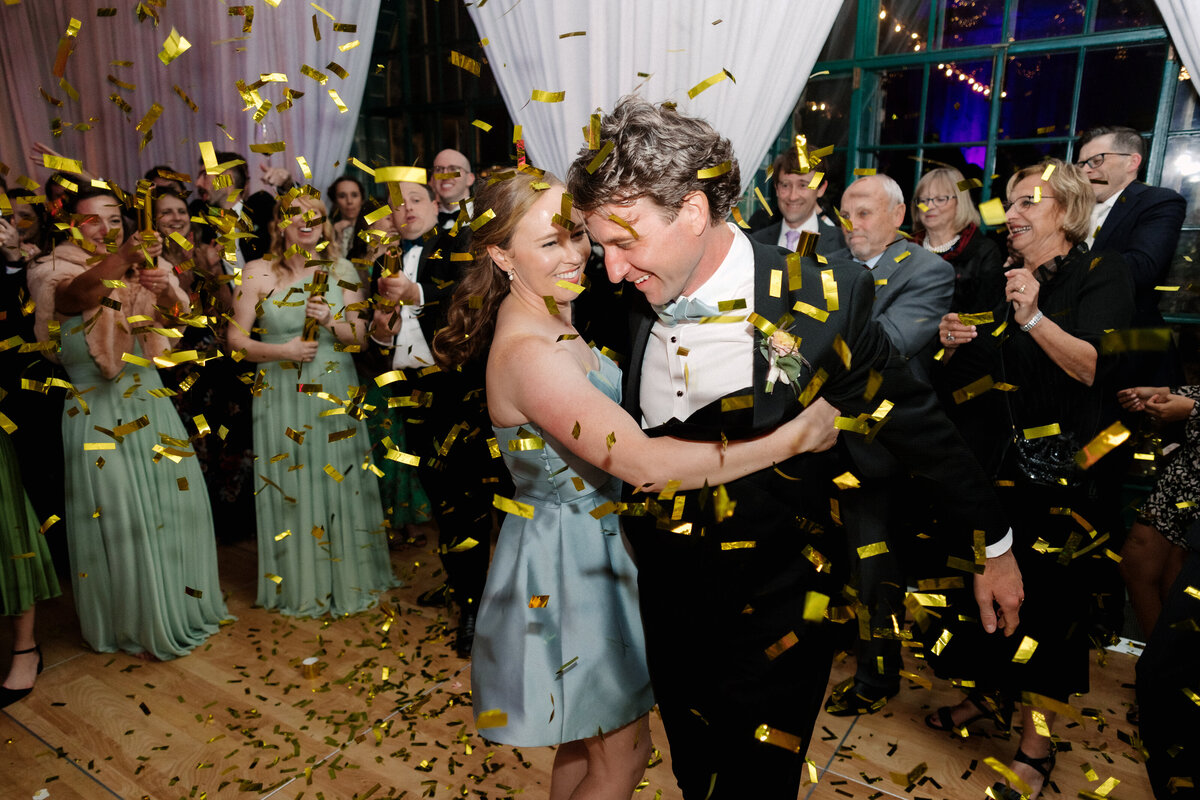 November wedding at Graylyn Estate, designed and planned by Charming Carolina — bride and groom dancing in the center of the dance floor as guests pop confetti cannons over them during the reception.