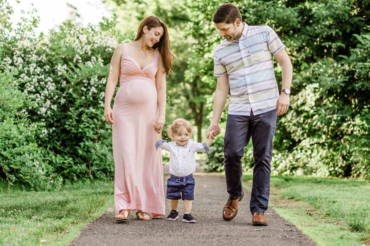 NJ Family Photo- man and woman holding little boy's hands in Maplewood, NJ park-SOMA life