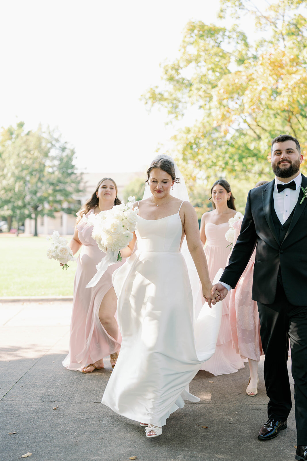 Bride and groom holding hands walking through Dearborn Village Michigan, soft natural light wedding photography.