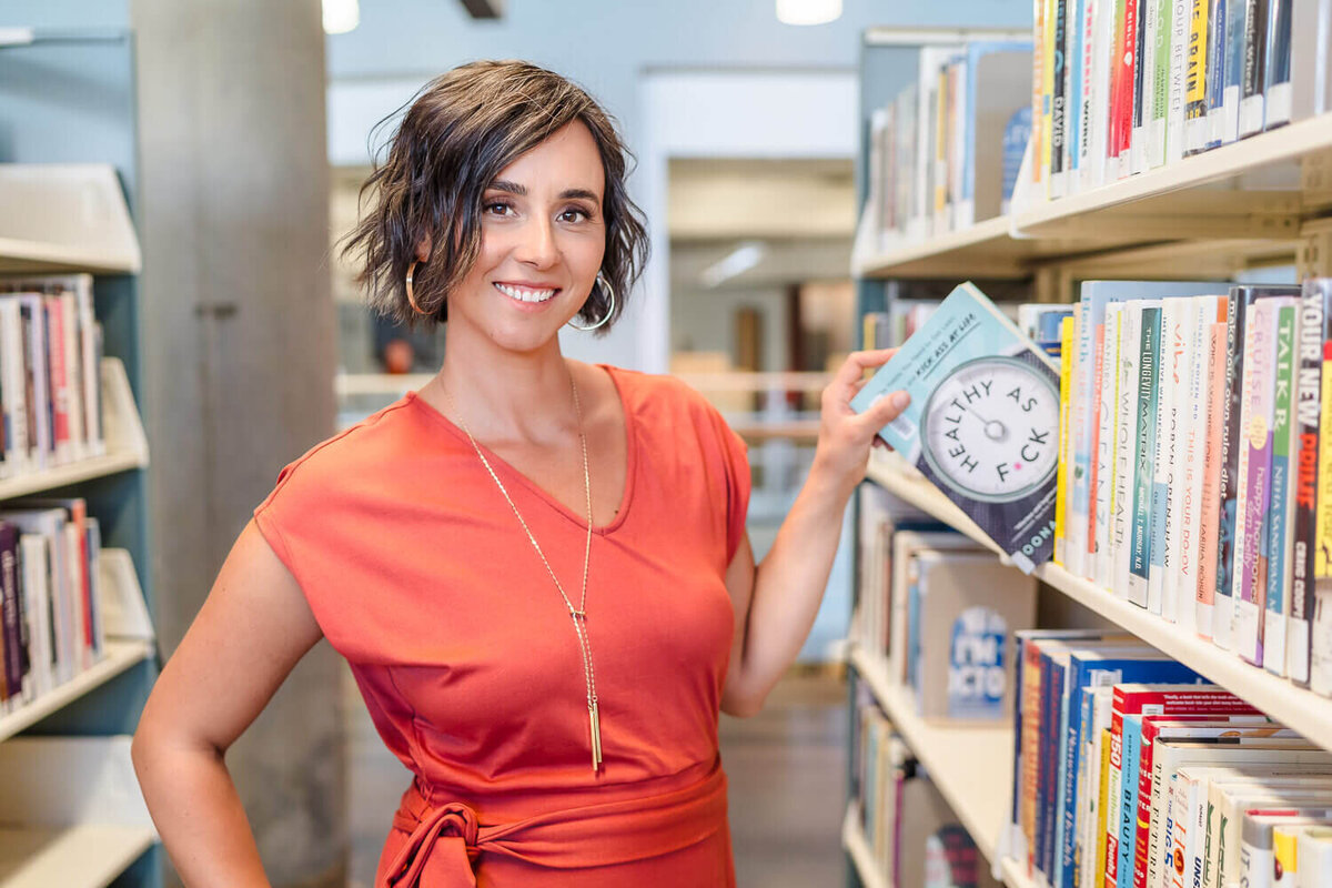 Woman in orange dress pulling a nutrition from the library bookshelf