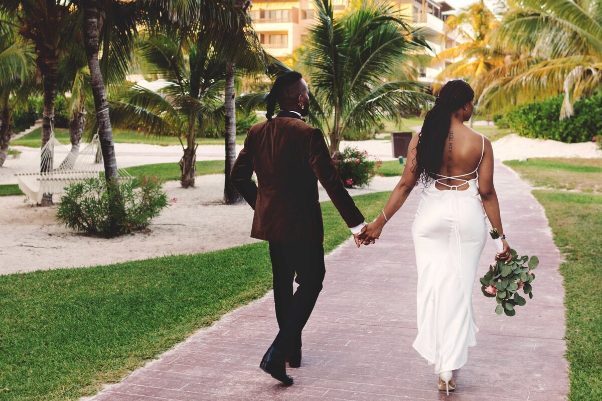Bride and groom walking down path at wedding in Cancun