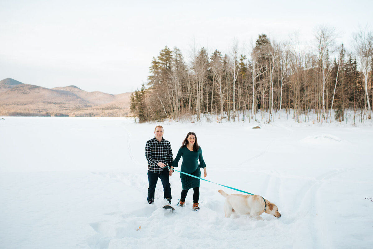 couple pregnant walking with dog in vermont